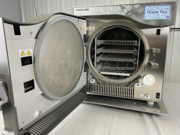 This is a front view of a Scican Statclave G4 autoclave with the door open showing the trays.